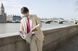 Indian businessman reading newspaper with buildings in background