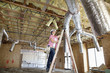 Young woman climbing up the ladder while looking at ceiling