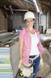Portrait of a happy young woman architect wearing hardhat at construction site