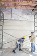 Male and female worker standing under scaffold at construction site