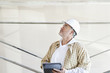 Photo: Mature male architect making a note in digital tablet while looking up at construction site Mature male architect making a note in digital tablet while looking up at construction site