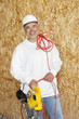 Photo: Portrait of a happy male construction worker holding a power saw and a red electric wire Portrait of a happy male construction worker holding a power saw and a red electric wire