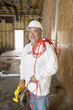 Photo: Portrait of a smiling male construction worker holding a power saw and a red electric wire Portrait of a smiling male construction worker holding a power saw and a red electric wire