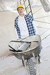 Male construction worker standing with a wheelbarrow