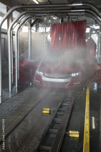 Photo : Vehicle on conveyor belt moving through car wash process Vehicle on conveyor belt moving through car wash process