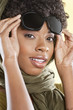 Portrait of an African American woman holding sunglasses with a stole round her neck over colored background
