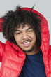 Portrait of a happy young man with hood over colored background