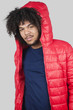 Portrait of young man wearing red jacket with hood over colored background