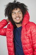 Happy young man wearing hooded jacket while looking away over colored background