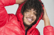 Portrait of a happy curly haired man with hands behind head over colored background