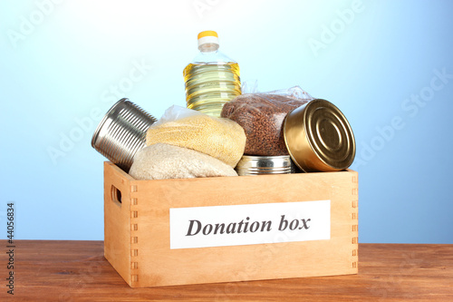 Photo: Donation box with food on blue background close-up Donation box with food on blue background close-up