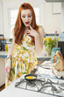 Beautiful young woman looking at omelet in frying pan