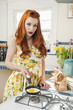 Portrait of a redheaded woman preparing omelet
