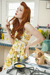 Young woman at kitchen counter thinking while looking up with hand on hip