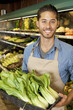 Photo: Portrait of handsome young sales clerk with bok choy in market Portrait of handsome young sales clerk with bok choy in market
