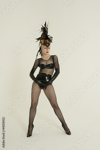 Photo: Pinup woman wearing fishnet stockings and leather posing over colored background Pinup woman wearing fishnet stockings and leather posing over colored background