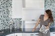 Beautiful young woman with color samples looking at contemporary kitchen cabinets