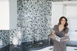 Beautiful young woman holding color samples while looking away in modern kitchen