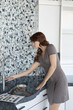 Young woman looking at faucet in model home kitchen