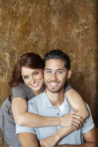 Photo: Portrait of happy young woman hugging man from behind Portrait of happy young woman hugging man from behind