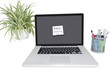 Smiley face sticky note on laptop with office supplies and pot plant