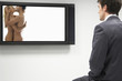 Businessman watching erotic naked couple on flat screen