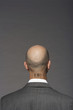 Bald headed businessman with barcode on his neck over gray background