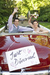 Photo : Happy couple in a convertible car waving with just divorced sign on it Happy couple in a convertible car waving with just divorced sign on it