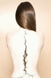 Rear view of a nude woman with a crack on spine over colored background