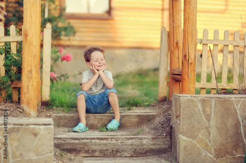 Photo: boy sits on a porch of the wooden house boy sits on a porch of the wooden house