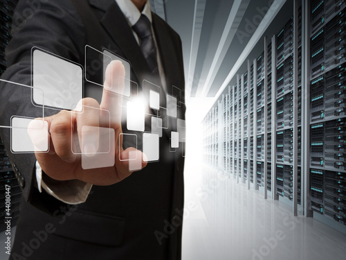 Photo: business man point virtual buttons in server room business man point virtual buttons in server room