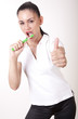 Young attractive girl cleaning her teeth and showing thumb up