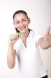 Young attractive girl cleaning her teeth and showing thumb up