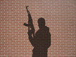 ombre d'homme armé sur briques rouges