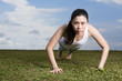 Fit Chinese woman doing push-ups at the park.