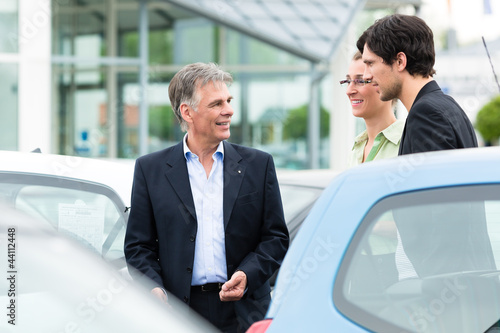 Photo: Autohändler und Kunden schauen ein Auto an Autohändler und Kunden schauen ein Auto an