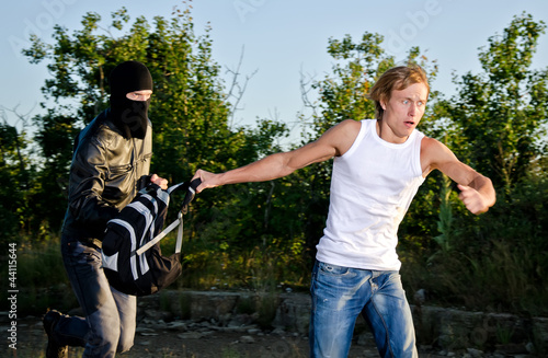 Photo: Thief in mask stealing a backpack Thief in mask stealing a backpack