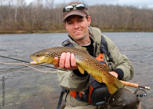 Photo: Fly fisherman with Brown Trout, fly rod and reel, in a river Fly fisherman with Brown Trout, fly rod and reel, in a river