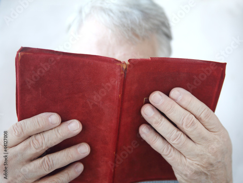 Photo: senior reads an old red leather-bound book senior reads an old red leather-bound book
