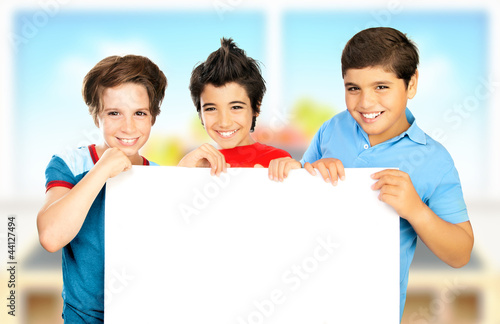 Photo: Three boys in classroom holding white clean board Three boys in classroom holding white clean board