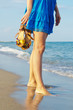 Woman holding her sandals on a beach