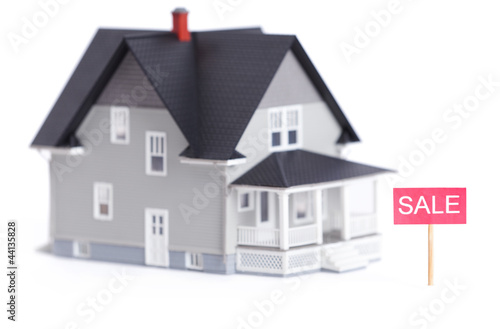 Photo: Household architectural model with sale sign, isolated on white Household architectural model with sale sign, isolated on white