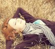 Young beautiful girl lying at yellow autumn field.