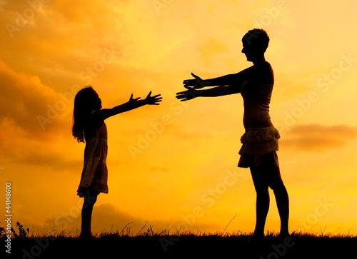 Photo: Silhouettes of mother and daughter meeting on the meadow Silhouettes of mother and daughter meeting on the meadow