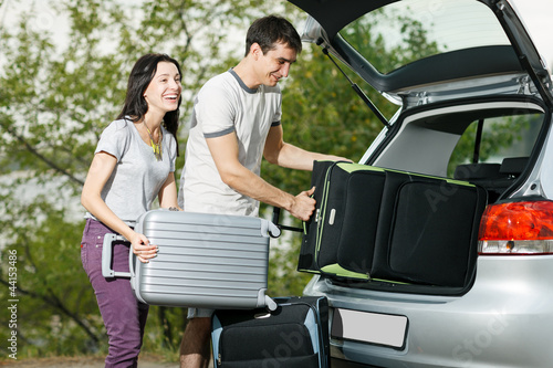 Photo: Happy couple going to vacations, loading their car boot Happy couple going to vacations, loading their car boot