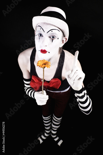 Photo: Mime in a white hat, holding a yellow flower Mime in a white hat, holding a yellow flower