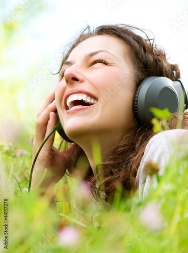 Photo: Beautiful Young Woman with Headphones Outdoors. Enjoy Music Beautiful Young Woman with Headphones Outdoors. Enjoy Music