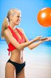Photo: Young woman playing with ball on beach Young woman playing with ball on beach