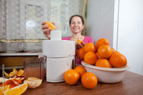 Photo: Mature woman making orange juice Mature woman making orange juice