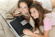 Foto: Jeunes filles avec ordinateur dans un lit Jeunes filles avec ordinateur dans un lit